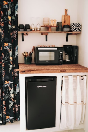 Eine Küche mit Mikrowelle, Kaffeemaschine und diversen Küchenutensilien auf einer Holzausziehtischplatte.