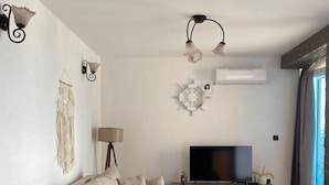 A living room with a sofa, a coffee table, a TV, and decorative wall art. - Sveti Stefan Panorama View Apartment (Sveti Stefan)