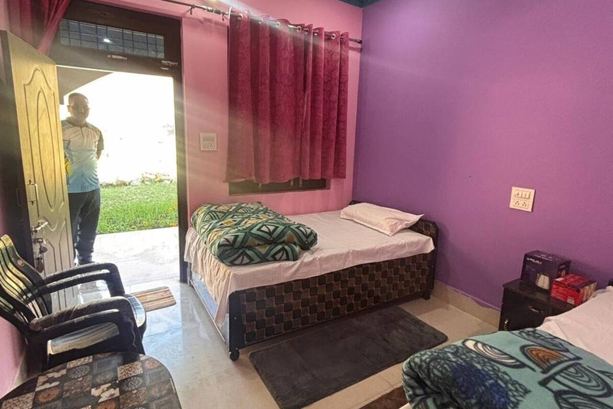 Un dormitorio con cama, una silla, un escritorio y una ventana con cortinas.