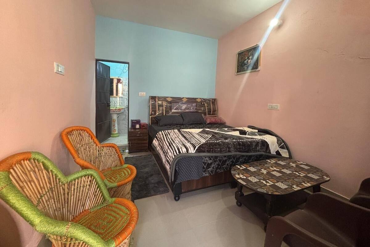 Un dormitorio con cama, dos sillas, una mesita y un espejo.
