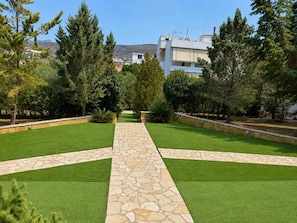 A landscaped garden with a stone pathway leading to a building. - Treasure B&B - Garden Stay in Paloukia Salamina (Paloukia)