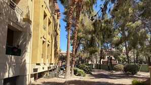 A courtyard with a building featuring balconies, a pathway, and surrounding trees. - Entire Condo just a short walk from the Strip! (Las Vegas)