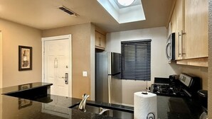 A kitchen with a stainless steel refrigerator, a microwave, a stove, a sink, and a skylight. - Entire Condo just a short walk from the Strip! (Las Vegas)