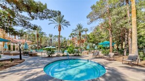 A pool area with lounge chairs, palm trees, and a clear sky. - Entire Condo just a short walk from the Strip! (Las Vegas)