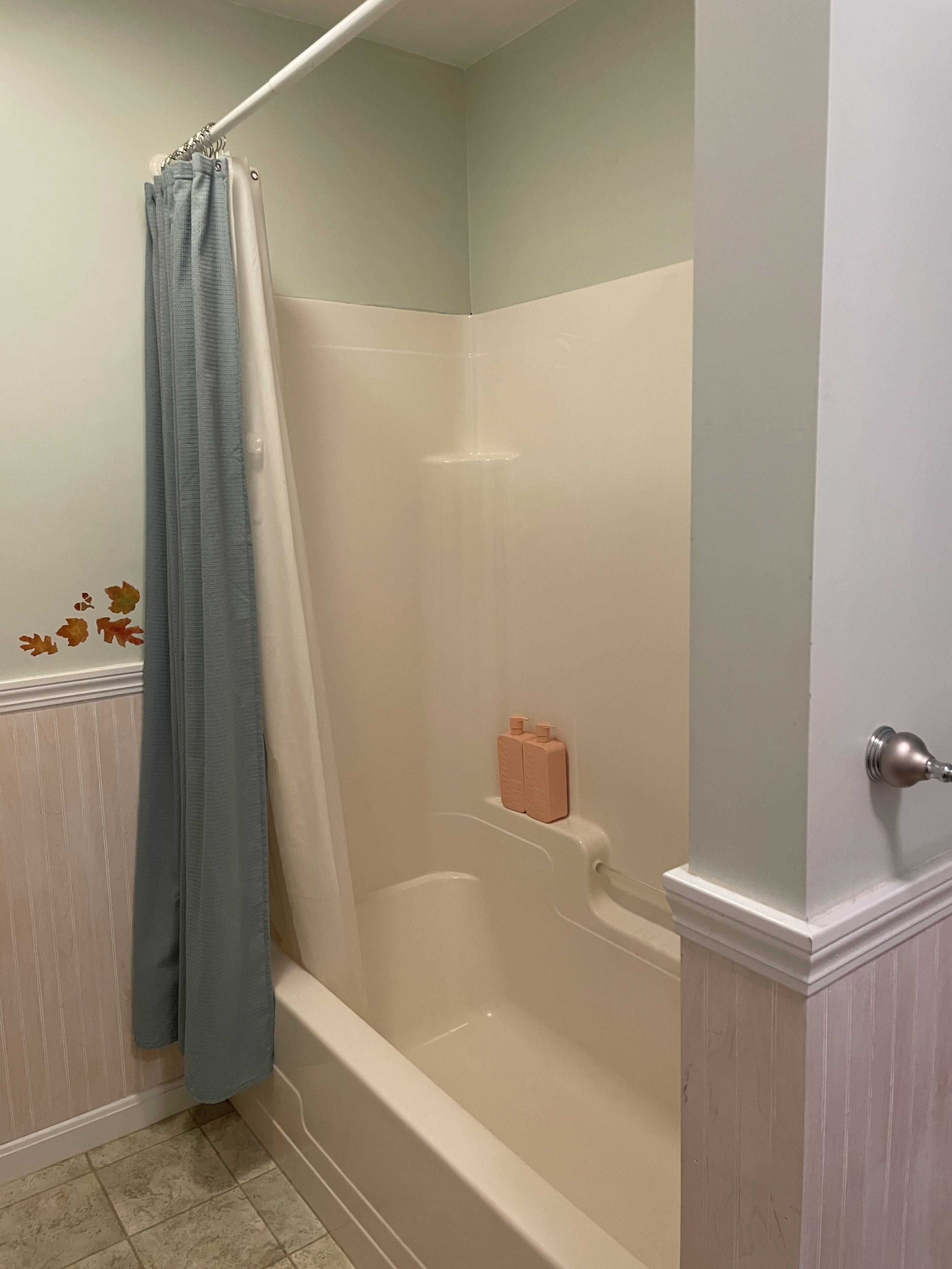 A bathroom with a shower curtain, a bathtub, and a toilet.