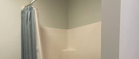 A bathroom with a shower curtain, a bathtub, and a toilet.