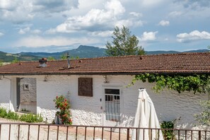 Um edifício rústico com telhado de telhas, parede de pedra e uma porta pequena.