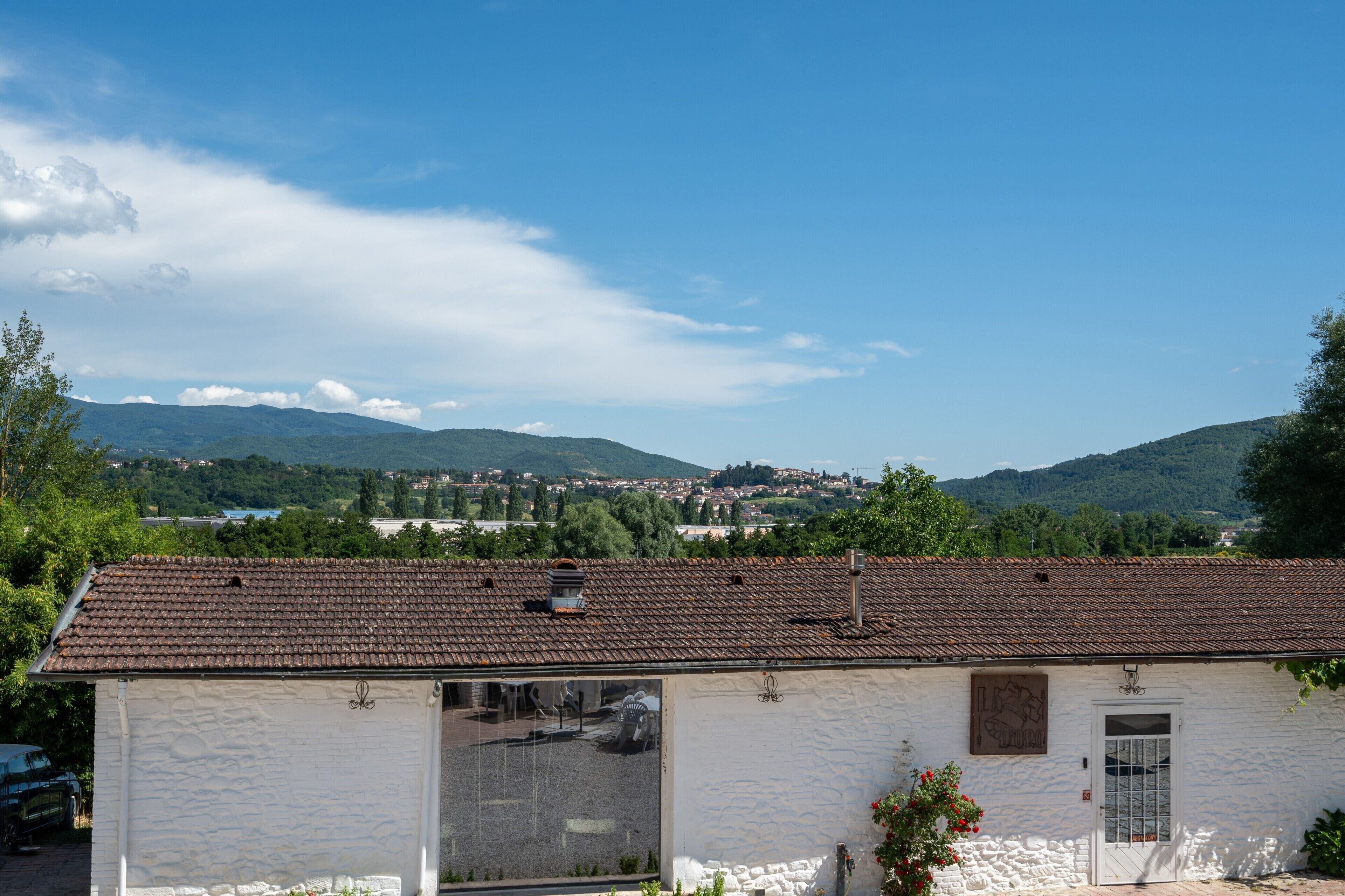 Un edificio blanco con techo de tejas, un ventanal y una puerta.