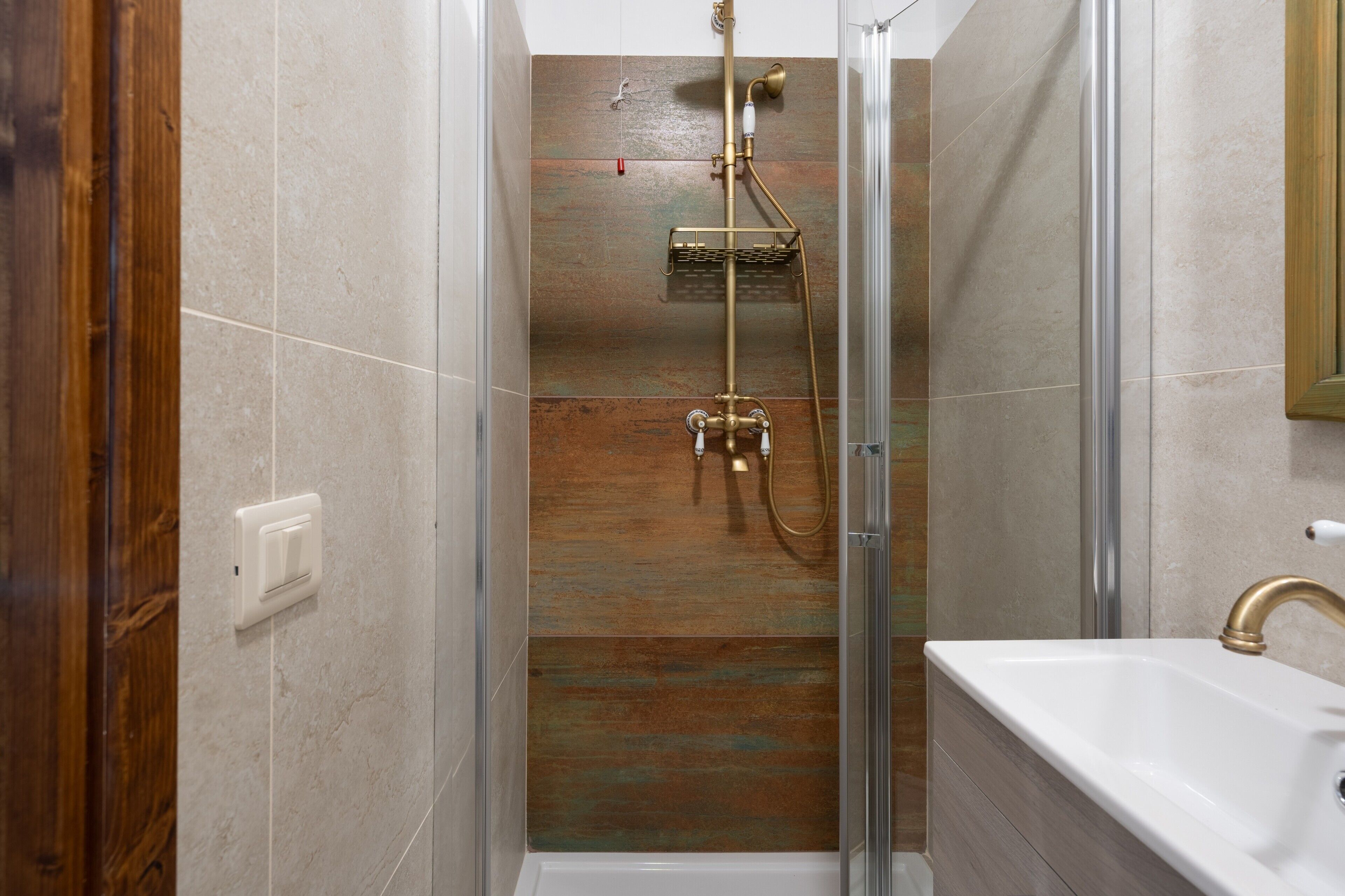 A shower with a glass door, a bathtub, and a wooden floor.