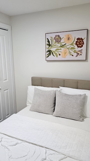 Ein Schlafzimmer mit einem Bett, Kissen, einem Kopfteil und einem floralen Wandbild.
