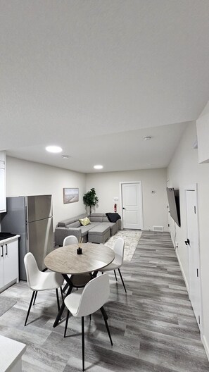 Eine moderne Küche mit Essbereich, grauem Sofa und einer kleinen Pflanze.
