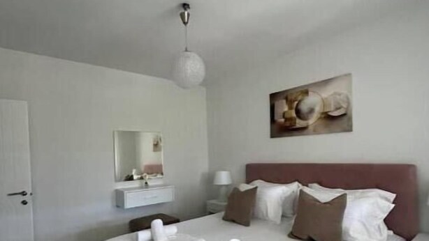 Ein Schlafzimmer mit einem Bett, Nachttischen, einer Lampe und einem Bild an der Wand.