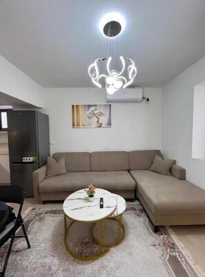Ein modernes Wohnzimmer mit Ecksofa, rundem Couchtisch und einer besonderen Pendelleuchte.