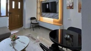 Ein modernes Wohnzimmer mit einer Couch, einem Esstisch und einem an der Wand befestigten Fernseher.