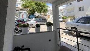 Ein Balkon mit Tisch und Stühlen, Blumentöpfen und Blick auf die Straße.