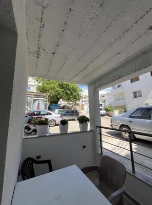 Ein Balkon mit Tisch und Stühlen, Blumentöpfen und Blick auf die Straße.