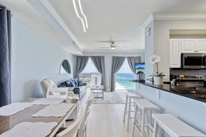 Ein modernes Wohnzimmer mit Meerblick, einem Essbereich und einer Küche mit Edelstahlgeräten.
