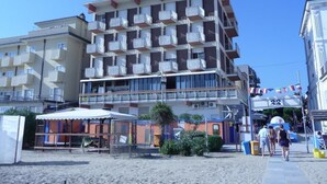 A multi-story hotel with balconies, a beachside location, and a visible entrance number. - Hotel Suprem sul Mare (Rimini)