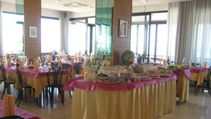 A banquet hall with round tables covered in yellow tablecloths and pink table runners, arranged in a semi-circle. - Hotel Suprem sul Mare (Rimini)