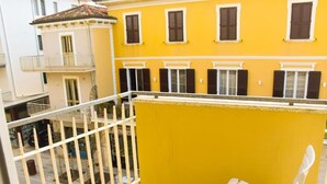 Un edificio amarillo con barandillas blancas, un banco blanco y múltiples ventanas con contraventanas.