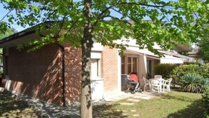 Un edificio de ladrillo con un patio cubierto, un cochecito de bebé y mobiliario exterior.