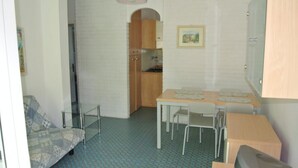 Habitación compacta con kitchenette, una mesa de comedor con sillas, un sofá y un televisor.