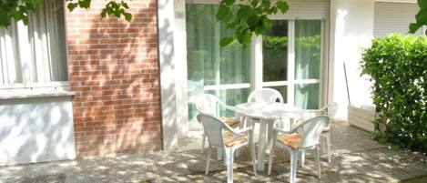 A patio with a table and chairs, a brick wall, and a glass door.