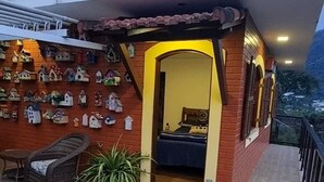A room with a bed, a chair, a potted plant, and a wall decorated with birdhouse ornaments. - Apartment with kitchenette, 2 bedrooms and private bathroom. (Teresópolis)