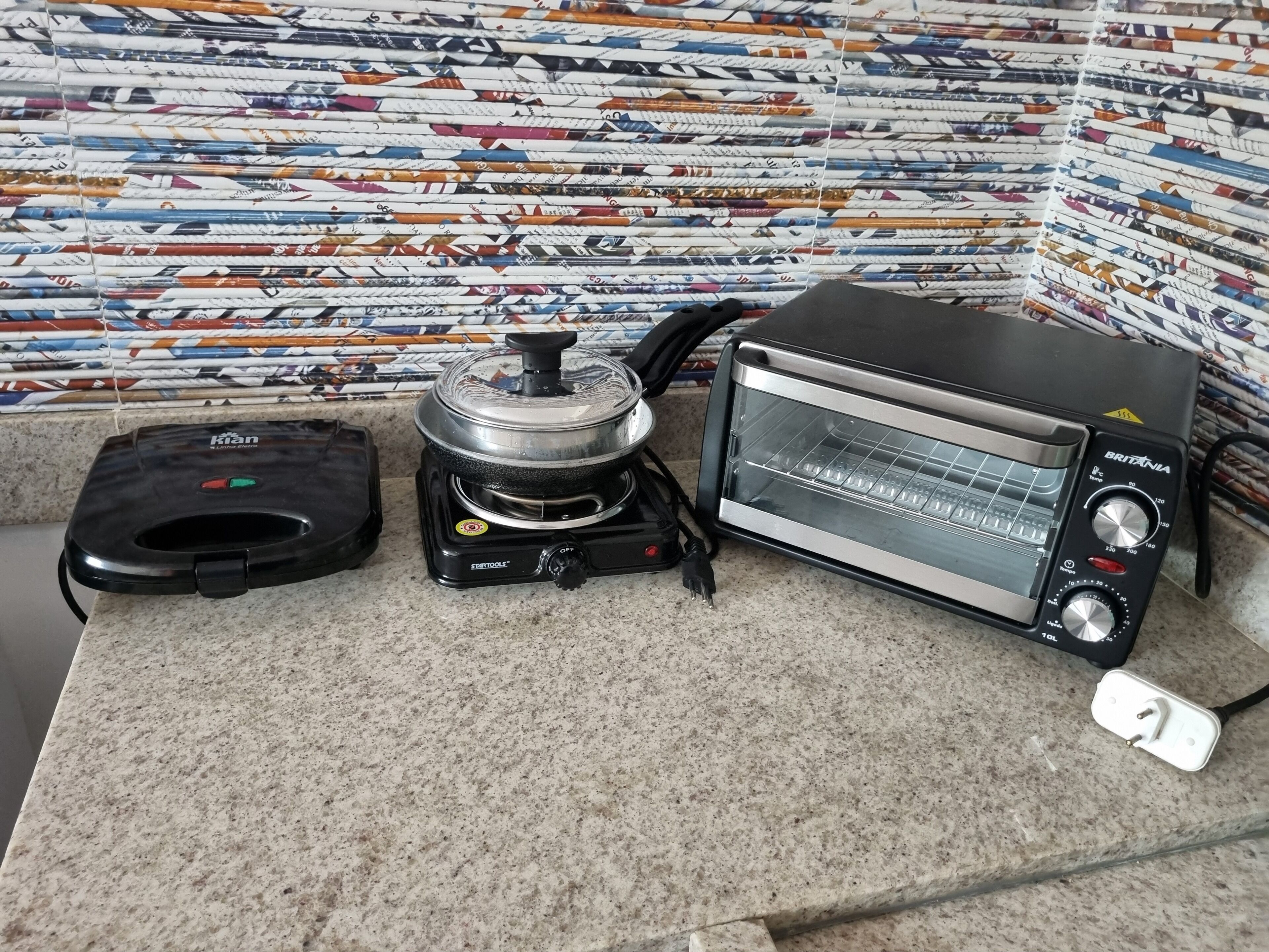 A kitchen with a toaster, a kettle, and a kettle lid on a granite countertop.
