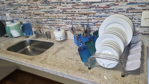 A kitchen with a granite countertop, a stainless steel sink, and a dish rack holding plates and bowls. - Apartment with kitchenette, 2 bedrooms and private bathroom. (Teres ópolis)