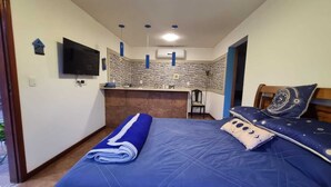 A bedroom with a bed, a TV, a small kitchenette, and a bathroom. - Apartment with kitchenette, 2 bedrooms and private bathroom. (Teresópolis)