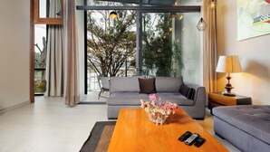 Una sala de estar moderna con un sofá, una mesa de centro con un florero y una lámpara, además de un control remoto de televisión sobre la mesa.