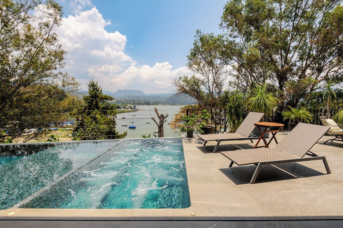 Une piscine dotée de chaises longues et offrant une vue sur un lac et des montagnes.