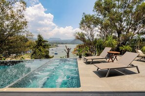 A swimming pool with lounge chairs and a view of a lake and mountains. - Villa del Carmen (San Gaspar)