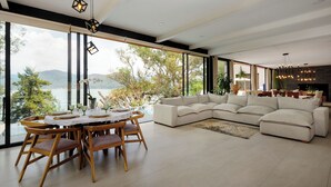 Una sala de estar moderna con un gran ventanal, un comedor y un sofá.