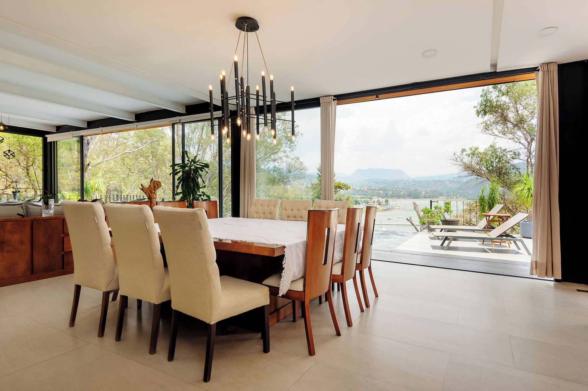 Un espace repas comprenant une table et des chaises, de grandes fenêtres et une vue sur l’extérieur.