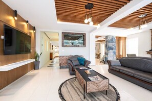 A modern living room with a flat-screen TV, a sofa, a coffee table, and a patterned rug. - The Infinities - Premium Villa Alexandros (Kos)