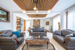 A modern living room with two sofas, a coffee table, and a fireplace. - The Infinities - Premium Villa Alexandros (Kos)