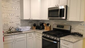 Eine moderne Küche mit weißen Schränken, einer Edelstahl-Mikrowelle, einem Gasherd und einem Backofen.