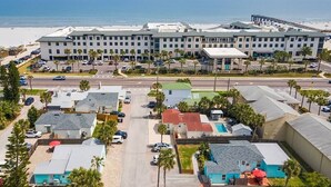 Ein Küstenhotel mit mehreren Gebäuden, einem Parkplatz und Blick auf den Strand.