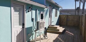 Ein Haus mit Eingangstür, einer kleinen Veranda, einem Holzzaun und einem Fahrrad.