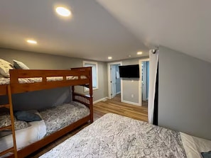A bedroom with bunk beds, a flat-screen TV, and a door leading to another room. - Peaceful and Spacious Home With Fenced Yard - 15 Min to Madison (McFarland)