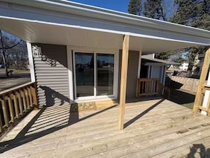 A covered deck with a wooden railing, a sliding glass door, and a small porch area. - Peaceful and Spacious Home With Fenced Yard - 15 Min to Madison (McFarland)