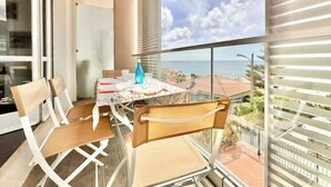 Un balcon avec une table et des chaises, une bouteille et une vue sur la mer.