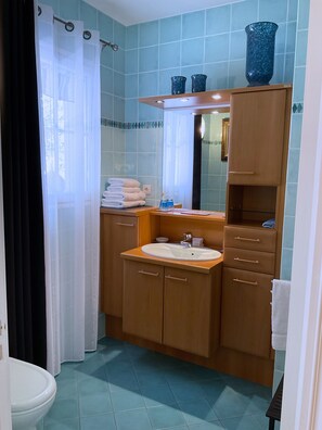 Een douche, handdoeken, zeep, toiletpapier