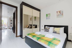 A bedroom with a bed, a wardrobe, and artwork on the wall. - Chic 2BDR East London Hideaway (Greater London)