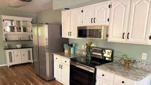 Una cocina con armarios blancos, un refrigerador de acero inoxidable, un microondas y un horno.