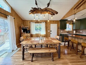 Un intérieur en bois comprenant une grande table à manger, un coin bar et une cuisine.