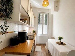 Eine kleine Küche mit einer Holz Arbeitsplatte, einem schwarzen Slow Cooker, einer Spüle und einem Fenster mit Fensterläden.