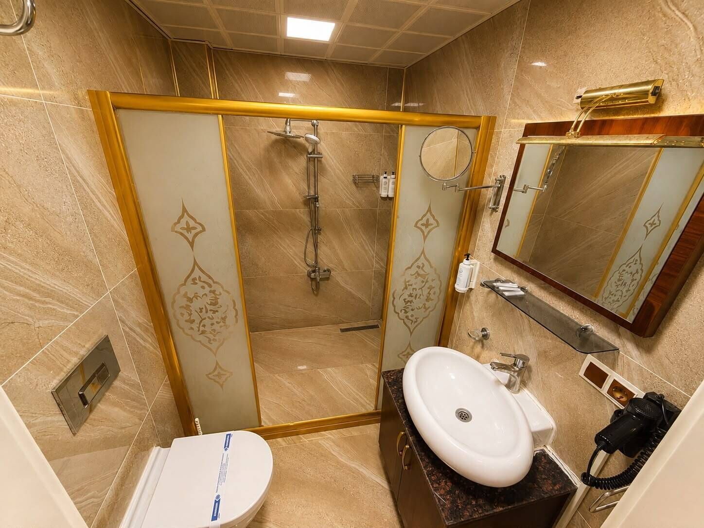 Baño con ducha, inodoro, lavamanos y espejo.